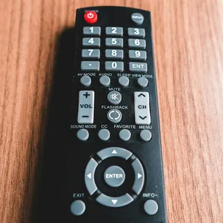 A black TV remote on a wooden table