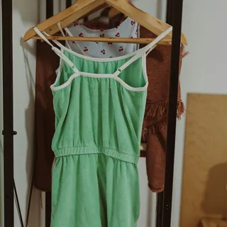 A green terry romper on a hanger